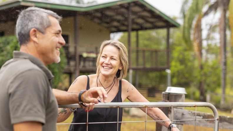 Middle aged man and woman standing at a country property gate.
