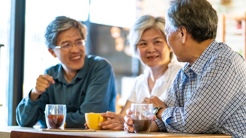 Three asian friends sitting at a table drinking coffee